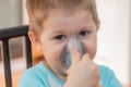 Little boy using nebulizer during inhaling therapy. Little boy making inhalation with nebulizer at home. Close up portrait of boy