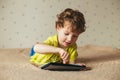 Cute little boy using a pad. Child playing with digital tablet lying on a bed. Free time. Tehnology and internet concept Royalty Free Stock Photo