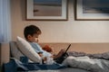 Little boy using tablet while laying in bed in living room.