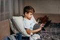Little boy using tablet while laying in bed in living room.