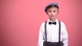 Little boy in vintage clothes looking into camera, isolated on pink background