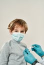 Little boy visiting doctor. Happy little boy in protective mask looking at camera while doctor in sterile gloves Royalty Free Stock Photo