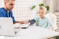 Little boy visiting doctor in hospital. Measuring blood pressure and checking pulse Royalty Free Stock Photo