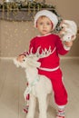 A little boy is waiting for christmas and having fun. the boy is riding a toy deer for Christmas