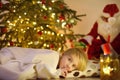 Little boy waiting Santa Claus under tree on Christmas Eve. Santa Claus brought gifts. Child not sleeping, but he does not show it Royalty Free Stock Photo