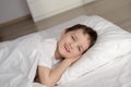 Little boy waking up in white bed with eyes open Royalty Free Stock Photo