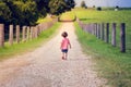 A little boy is walking alone on the country road farm into a br