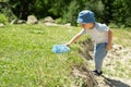 Little boy is walking with butterfly net and catching butterflies on green hills on sunny summer day Royalty Free Stock Photo