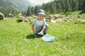 Little boy is walking with butterfly net and catching butterflies on green hills on sunny summer day Royalty Free Stock Photo