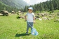 Little boy is walking with butterfly net and catching butterflies on green hills on sunny summer day Royalty Free Stock Photo