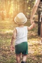 Little boy walking with mom in park.