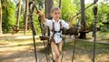 Little boy walking over rope bridge at outdoor amusement park. Active childhood, healthy lifestyle, kids playing outdoors,