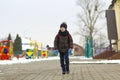 Little boy walking in the park. Child going for a walk after school with a school bag in winter. Children activity outdoors in fre Royalty Free Stock Photo