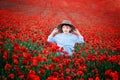 Little boy walking in poppy field. Very happ child boy in the cute hat in poppy field