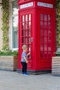 A little boy wants to enter a red phone booth.