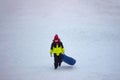 A little boy in warm bright outerwear carries a sled Royalty Free Stock Photo