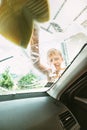 Little Boy washing front car window with soap foamy sponge. Inside car camera view