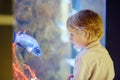 Little boy watches fishes in aquarium. Child exploring nature. Elementary student is on excursion in seaquarium Royalty Free Stock Photo