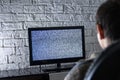 Little boy watching lcd TV in a dark room with loft style brick walls, backside view. Royalty Free Stock Photo