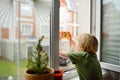 Little boy watching the rain outside at opened window and taking photo. Bad weather - wind and downpour. Inquisitive child explore Royalty Free Stock Photo