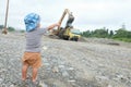 Little boy watching truck loaded with sand by excavator Royalty Free Stock Photo