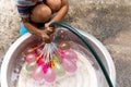 Little boy with water hose filling colorful water balloons in bucket. Royalty Free Stock Photo