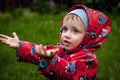 Little boy in a waterproof jacket in tractors catch the rain. Child having fun outdoors in summer shower