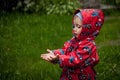 Little boy in a waterproof jacket in tractors catch the rain. Child having fun outdoors in summer shower