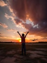 Little boy waving both hands to the plane in the air. Beautiful sunset sky with pink clouds at backdrop. Generative AI