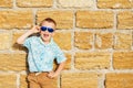 little boy wearing blue mirror sunglasses against the yellow brick wall outdoors Royalty Free Stock Photo