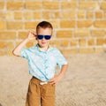 little boy wearing blue mirror sunglasses against the yellow brick wall outdoors Royalty Free Stock Photo