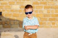 little boy wearing blue mirror sunglasses against the yellow brick wall outdoors Royalty Free Stock Photo