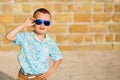 little boy wearing blue mirror sunglasses against the yellow brick wall outdoors Royalty Free Stock Photo