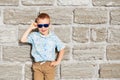 little boy wearing blue mirror sunglasses against the yellow brick wall outdoors Royalty Free Stock Photo