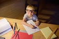 Little boy wearing glasses doing homework, painting and writing at home evening. Preschooler learn lessons - draw and color image Royalty Free Stock Photo