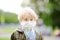 Little boy wearing medical face mask as protection against infectious diseases