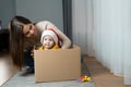 A little boy wearing a Santa Claus hat sits in a box on the floor next to his Caucasian mother. Happy family on Royalty Free Stock Photo