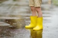 Little boy wearing yellow rubber boots walking on rainy summer day in small town. Child having fun. Outdoors games for children in Royalty Free Stock Photo
