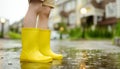 Little boy wearing yellow rubber boots walking on rainy summer day in small town. Child having fun. Games for children in rain Royalty Free Stock Photo