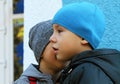 Little boy whispers a secret to his friend wearing winter hats