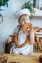 little boy in white chef uniform holding a loaf and candy in the bakery, bread shop Royalty Free Stock Photo