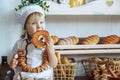 little boy in white chef uniform holding a loaf and candy in the bakery, bread shop Royalty Free Stock Photo
