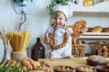 little boy in white chef uniform holding a loaf and candy in the bakery, bread shop Royalty Free Stock Photo