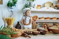 little boy in white chef uniform holding a loaf and candy in the bakery, bread shop Royalty Free Stock Photo