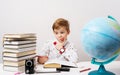 A little boy in a white shirt with a big car smart watch on his hand does his homework for school.