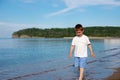 a little boy in a white t-shirt and blue shorts walks along the sea Royalty Free Stock Photo