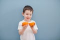 Little boy in white t-shirt holds two orange slices Royalty Free Stock Photo