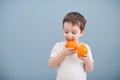 Little boy in white t-shirt holds two orange slices Royalty Free Stock Photo