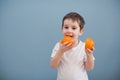 Little boy in white t-shirt holds two orange slices Royalty Free Stock Photo