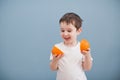 Little boy in white t-shirt holds two orange slices Royalty Free Stock Photo